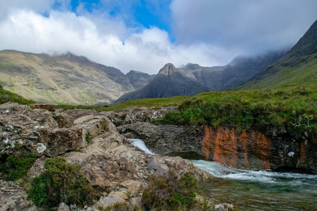 an idyllic scottish landscape with mountains in the background and a stream in the foreground